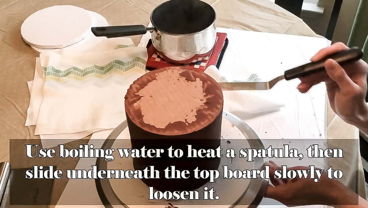 Sliding spatula under top board on cake.