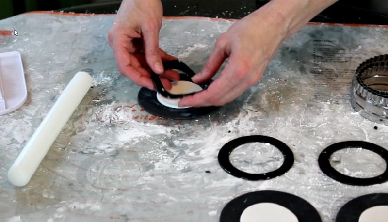 attaching black fondant ring onto fidget spinner cake