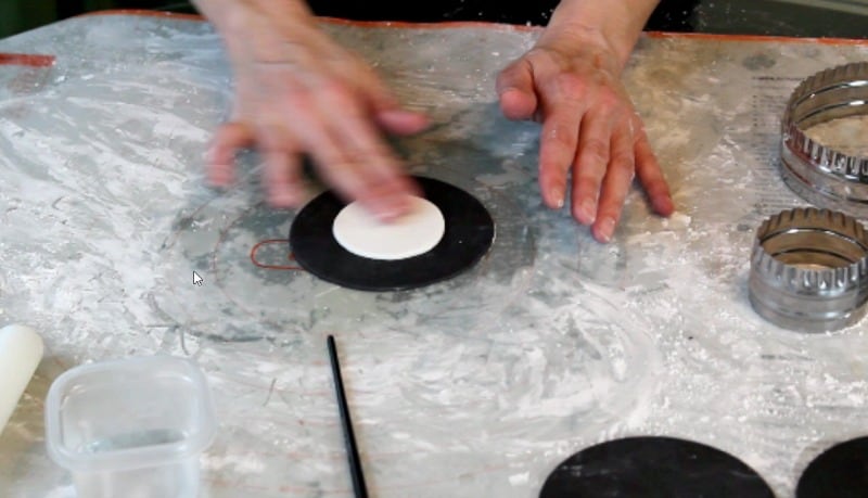 attaching white fondant circles for fidget spinner cake