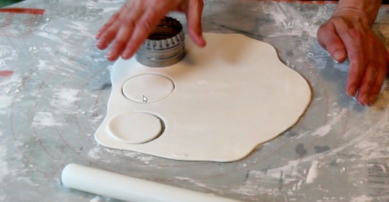 cutting out white fondant circles for fidget spinner cake
