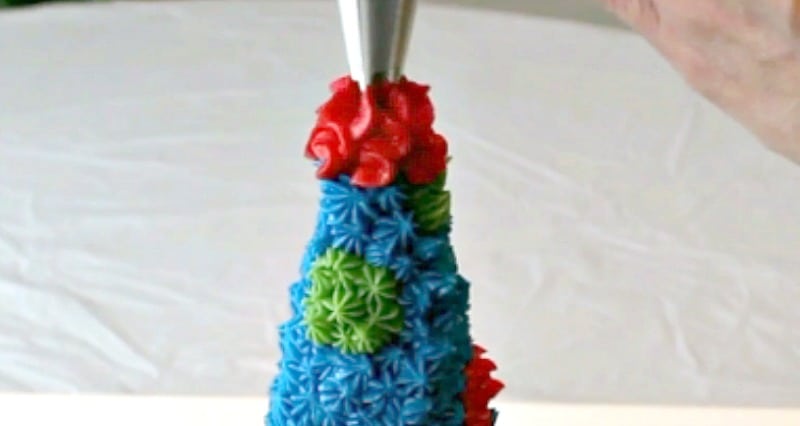 Piping buttercream on top of rice krispie party hat cake topper