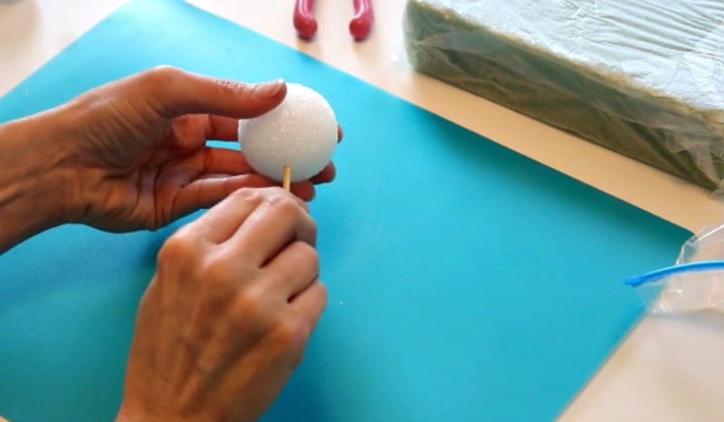 Inserting dowel into styrofoam ball