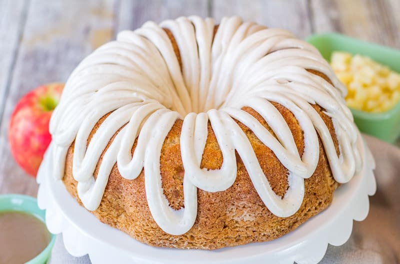 Moist Apple Coconut Cake with Cinnamon Cream Cheese Glaze on a white cake stand