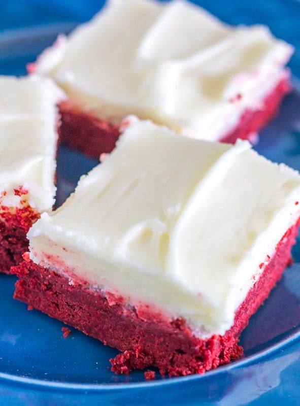 Cream Cheese Buttercream on red velvet cake bars on blue plate
