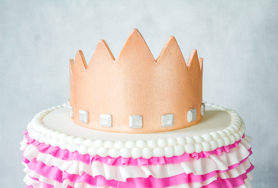 Gold gumpaste crown on top of ruffle cake