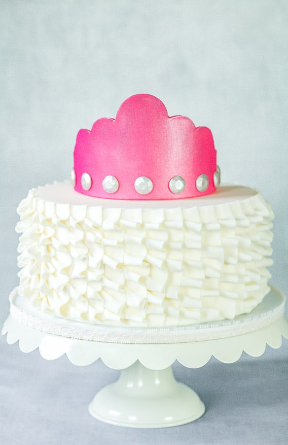 Hot pink gumpaste crown on top of ruffle cake