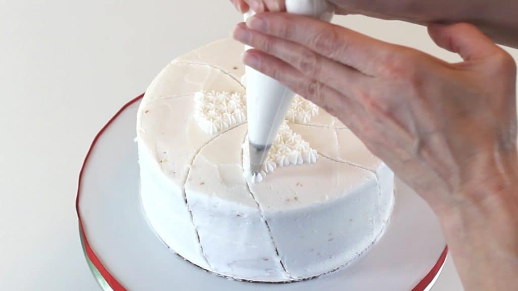 Piping white stars onto cake