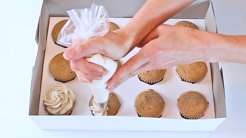 piping onto cupcakes in a box