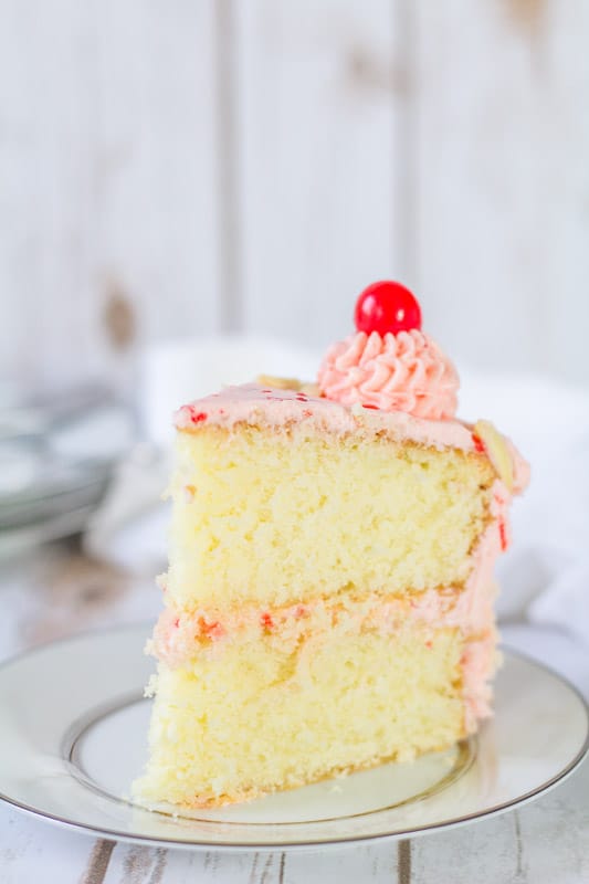 almond cake with cherry buttercream sliced on a white plate