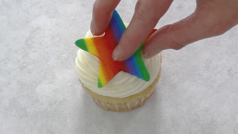 attaching rainbow buttercream shape star to cupcake