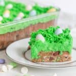 Slice of easter bar blondie on a white plate with green grass icing