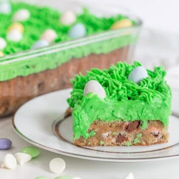 Slice of easter bar blondie on a white plate with green grass icing