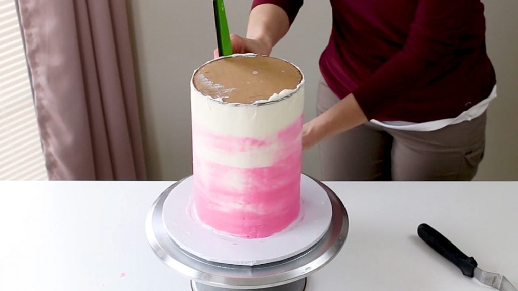 Smoothing watercolor buttercream on tall cake