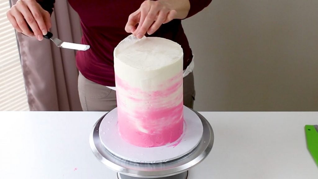 Taking off the wax paper on the top of the tall cake