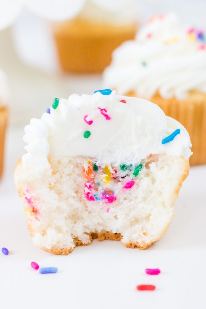 Funfetti Filled Cupcake with bite taken out with cupcakes in background