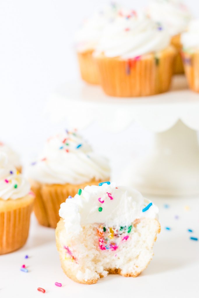 Funfetti Filled Cupcakes on a cake stand with sprinkles