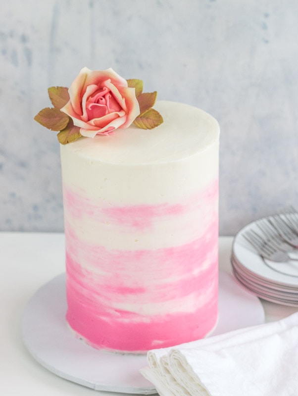 tall pink and white cake with pink rose
