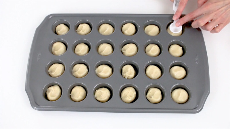 Pressing cookie dough into mini muffin pan to make cookie cups