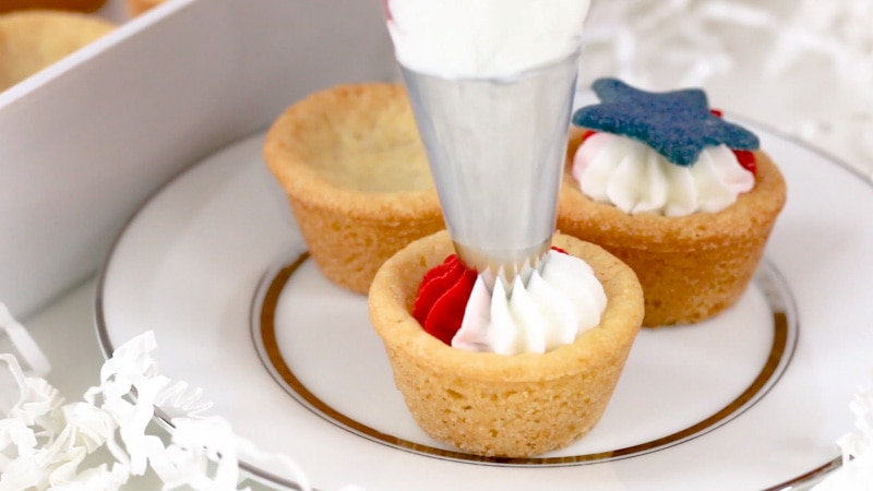 Adding buttercream to patriotic cookie cups