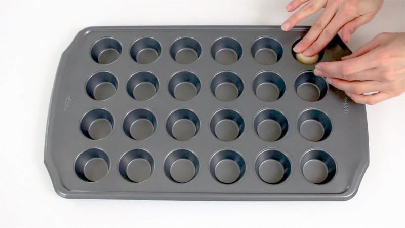 Adding cookie dough to mini muffin pan to make cookie cups
