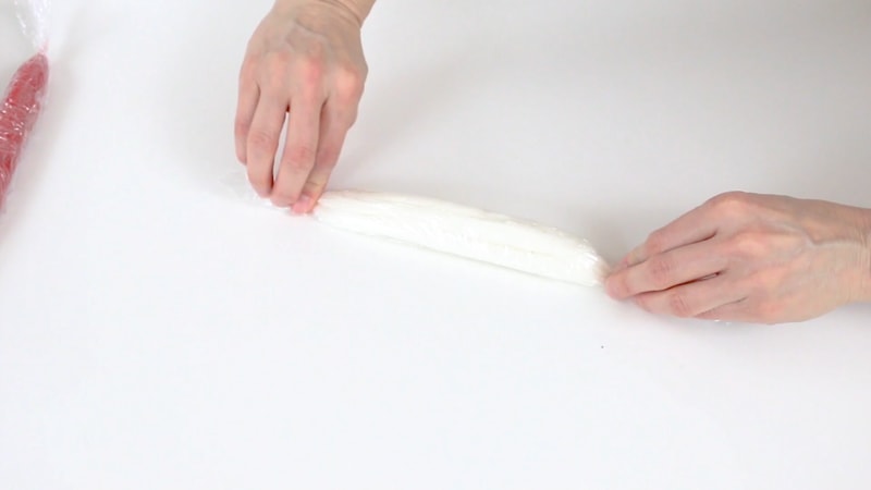 Rolling up white buttercream in saran wrap