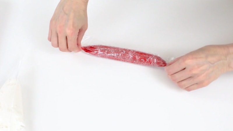 Rolling up red buttercream in saran wrap