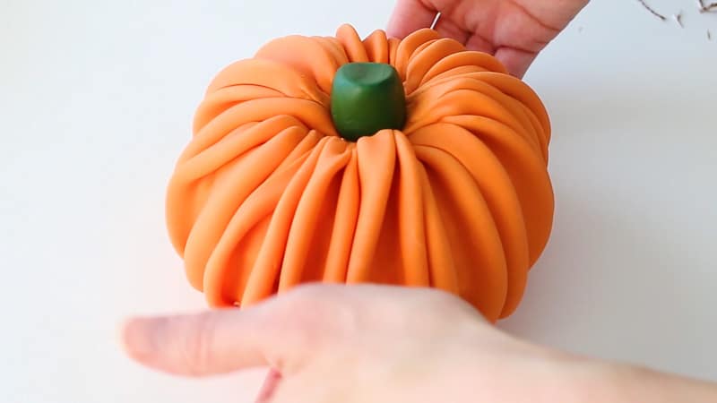 setting the fondant pumpkin onto the cake base