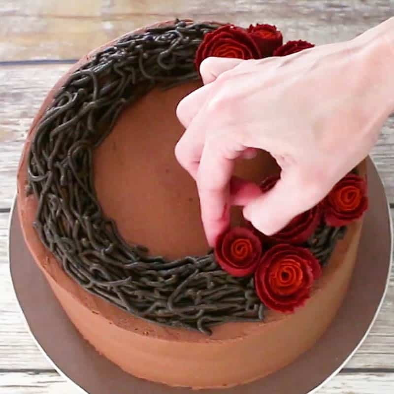 Adding buttercream roses to cake