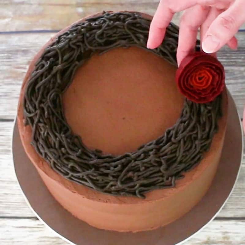 Adding buttercream roses to cake