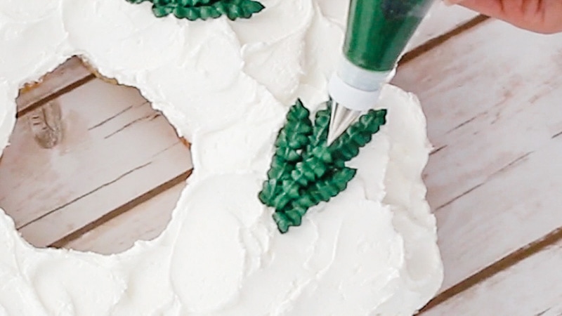 piping leaves onto cupcake wreath cake