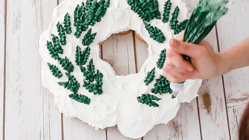 piping leaves onto wreath cake