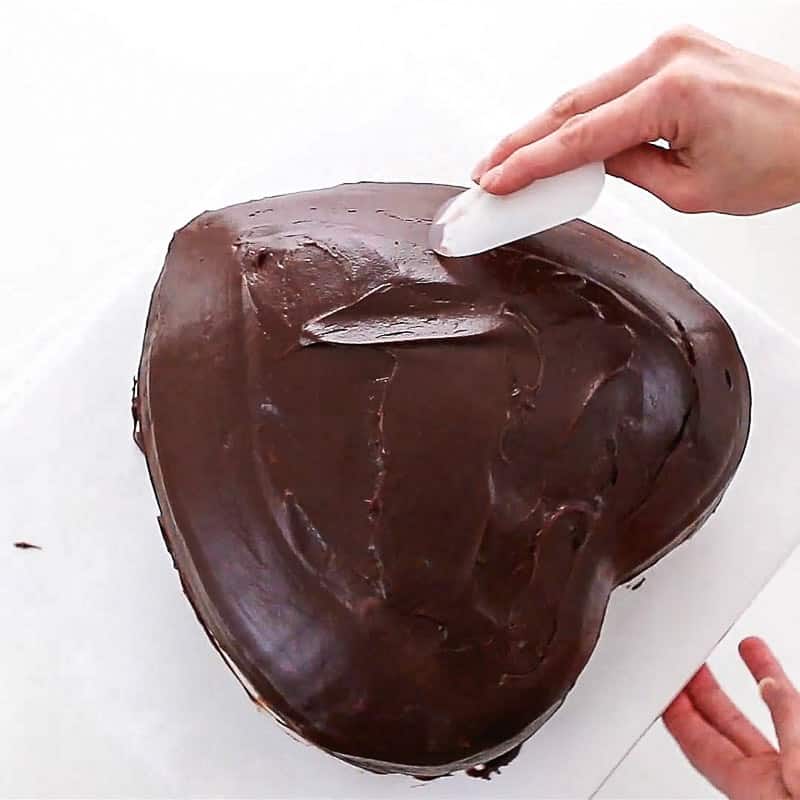 smoothing ganache on heart cake