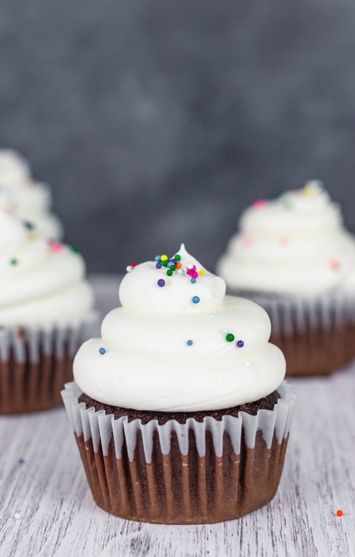 Chocolate cupcake with fluffy white icing with sprinkles.