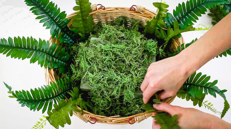 adding faux greenery to cupcake bouquet basket