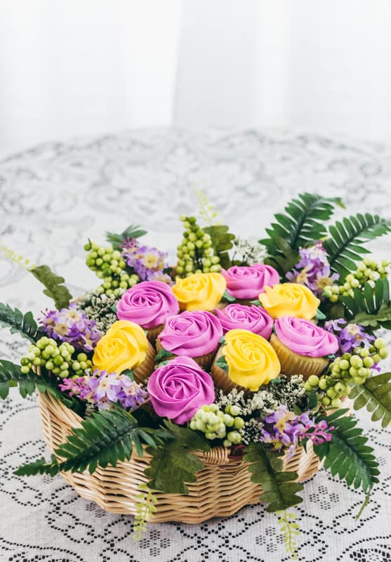 cupcake bouquet in a baset with pink and yellow roses