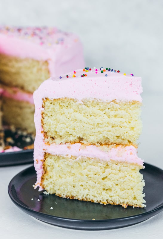 Large slice of vanilla cake with pink icing and sprinkles
