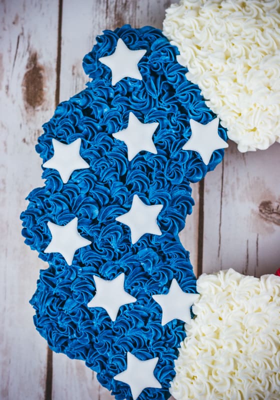 Close up of blue rosettes and white stars on cupcake cake