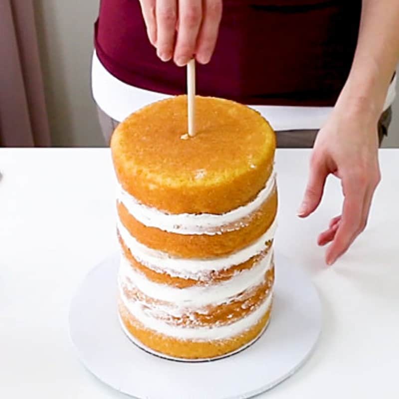 Adding a tall middle dowel into a multilayered cake.