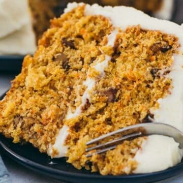 Close up of carrot layer cake with fork on a plate.