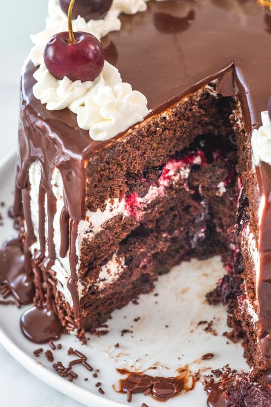 sliced chocolate cake with cherry filling and whipped cream