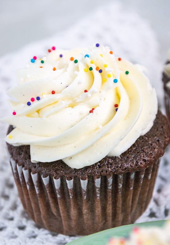 fluffy white icing on a chocolate cupcake with sprinkles