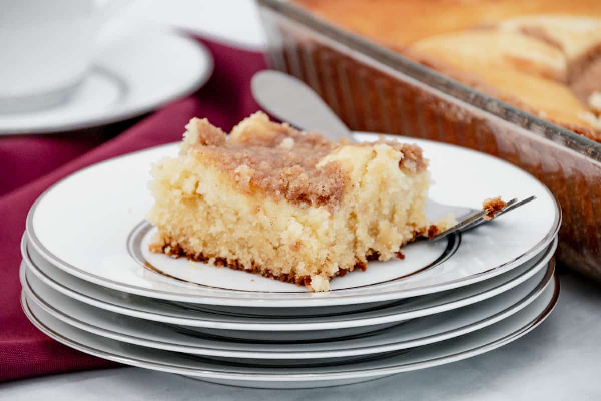 Piece of cream cheese crumb cake on white plates with a fork.