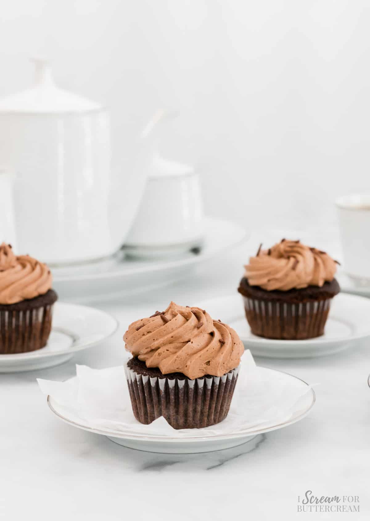 Image of three chocolate cupcakes on white plates.
