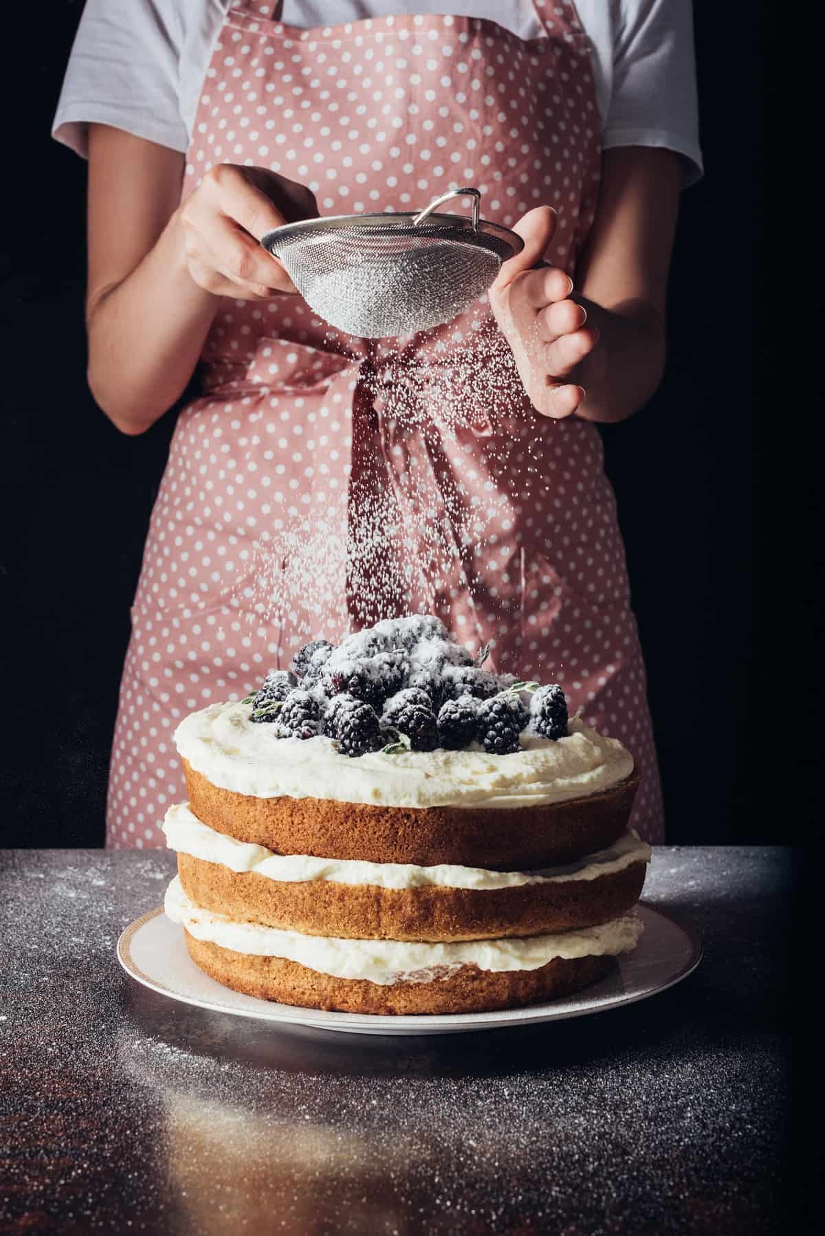 Sprinkling powdered sugar onto cake.