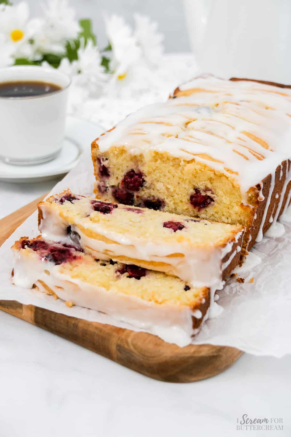 Cut lemon and blackberry bread on a plate with coffee.