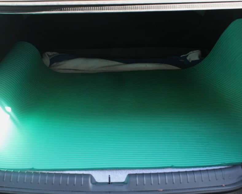Green yoga mat in the trunk of a car.