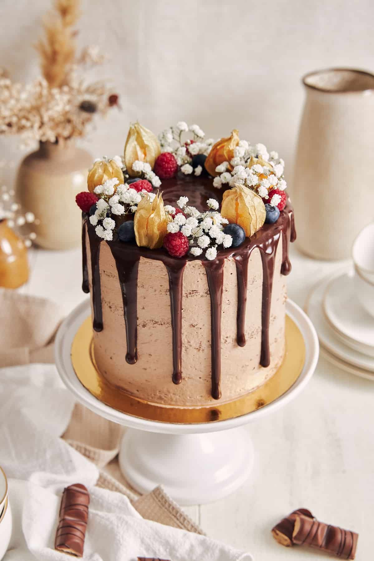 Chocolate cake with drip on a white pedestal.