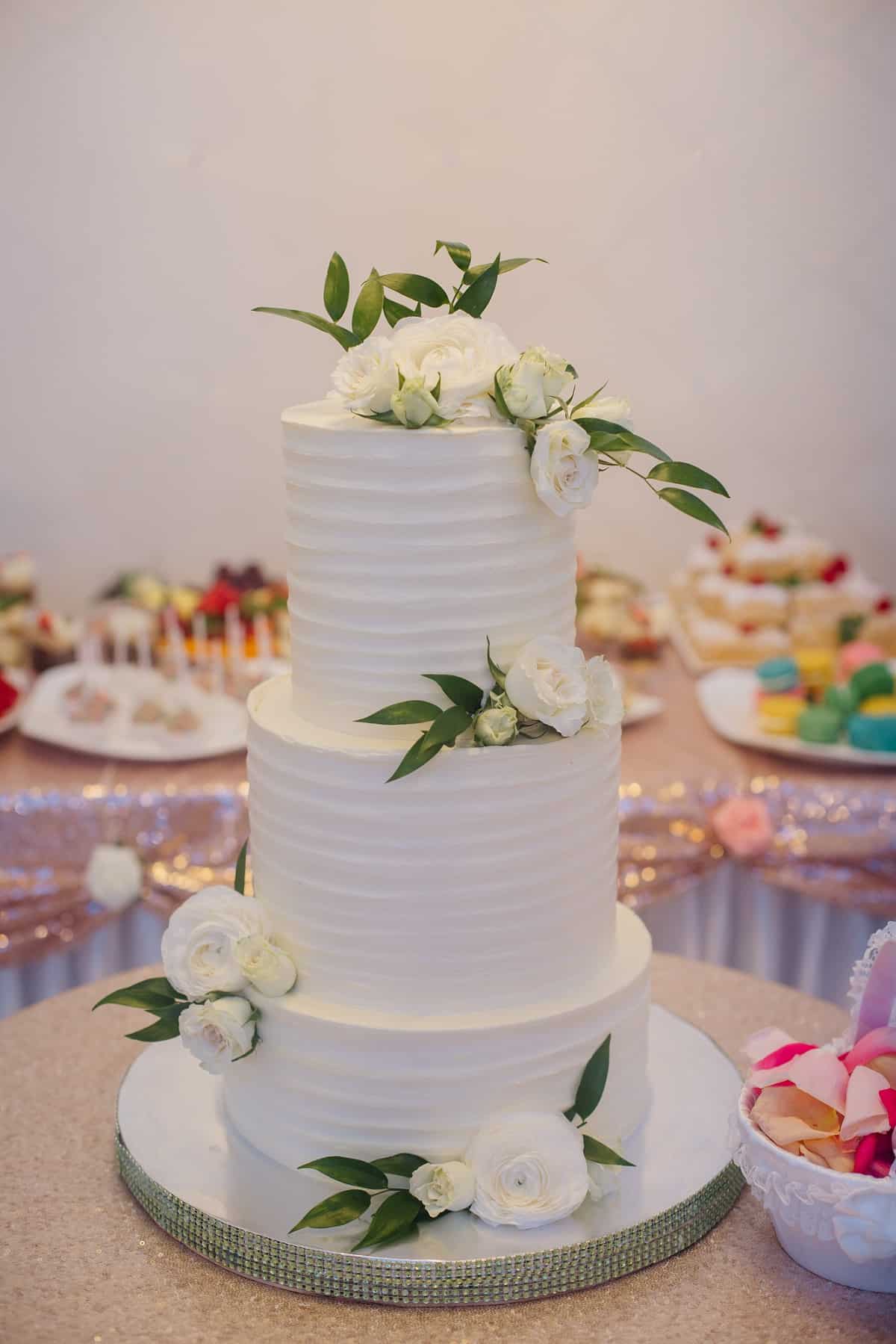 Three tiered white cake with white flowers.