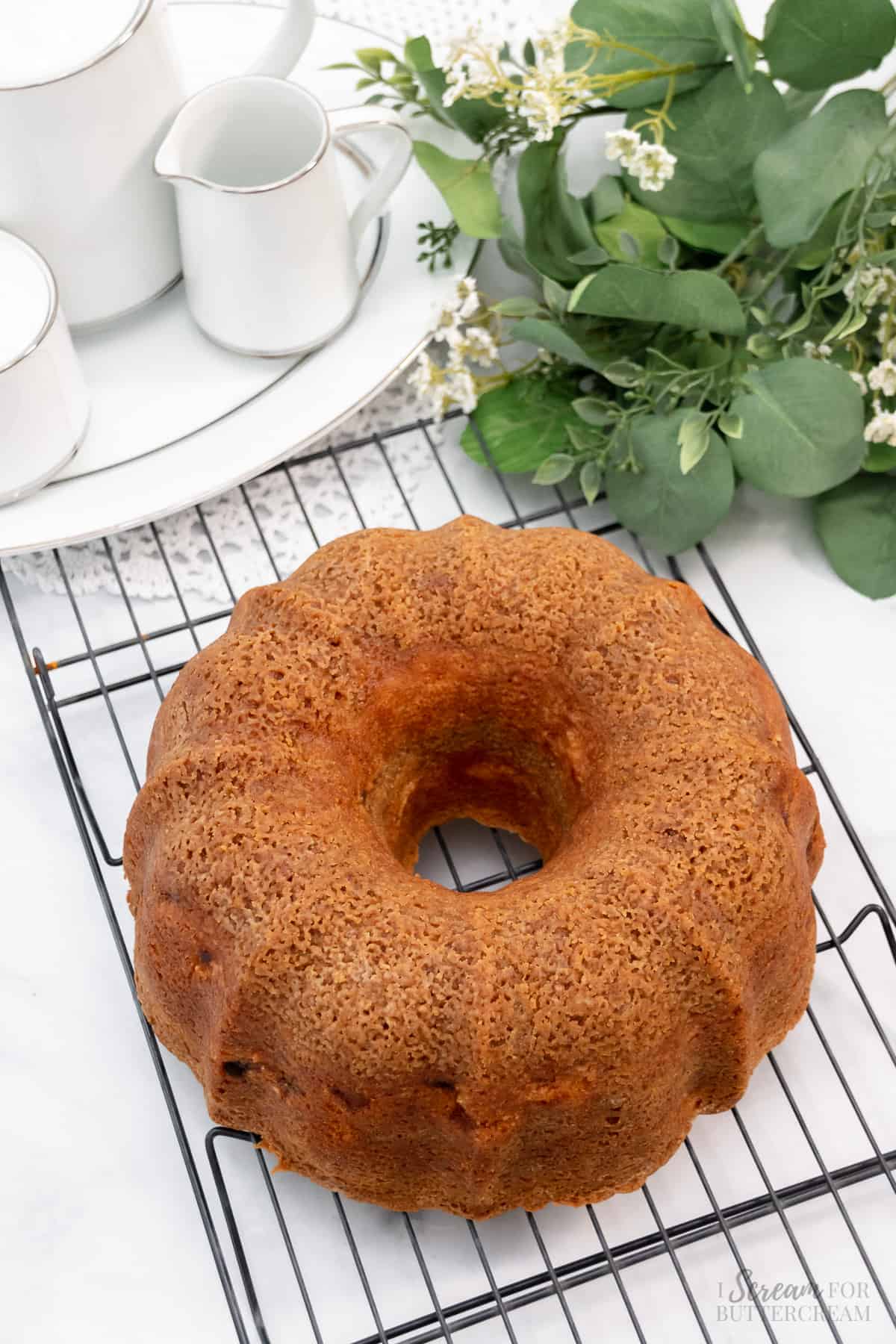 Baked and cooling bundt cake with peaches on a cooling rack.