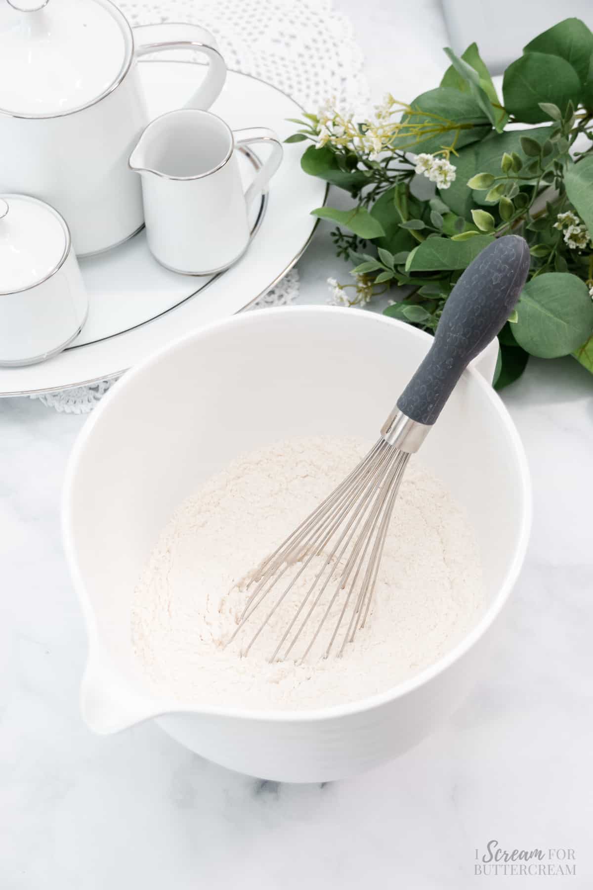 Mixing dry ingredients for pound cake in a white bowl.